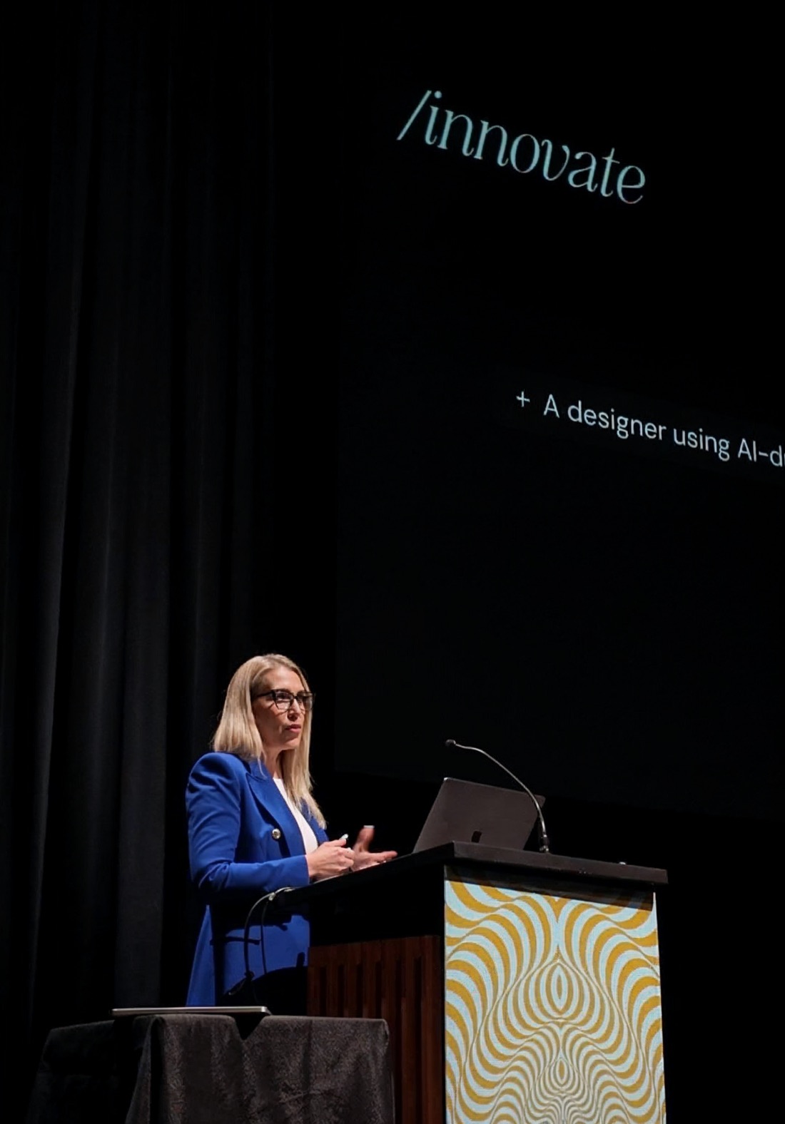 Ashlea speaking at a podium at Design Thinkers 2024